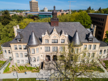 An aerial image of Denny Hall during the daytime with the UW Tower visible in the distance