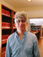 Man with curly grey hair and glasses