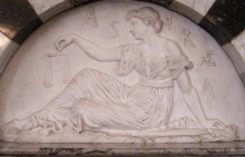 marble relief sculpture of seated woman in profile holding a balance scale