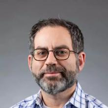 Person in plaid shirt with beard and glasses