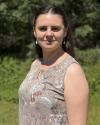 Photo of a white woman with brown hair wearing a green shirt