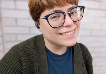 image of Cat Chase in a green sweater and blue shirt and glasses