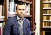 Man seated in front of bookshelves