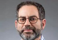 Person in plaid shirt with beard and glasses