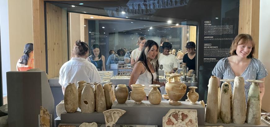 Students look at items of various materials in museum cases